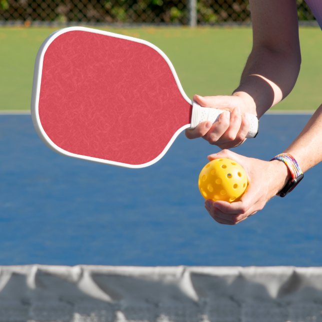 Red textured surface with subtle swirling pattern pickleball paddle (Insitu)