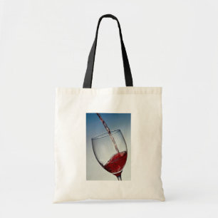 Red wine poured into wine glass tote bag