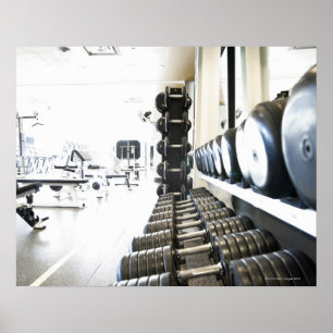 Row of free weights in foreground and exercise poster
