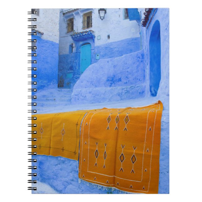 Rugs Draped On A Blue Wall Notebook (Front)