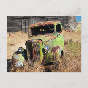 Rusting car in front of abandoned farm postcard