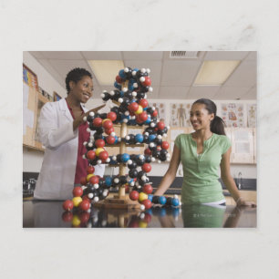 Science teacher and teenage girl looking at postcard