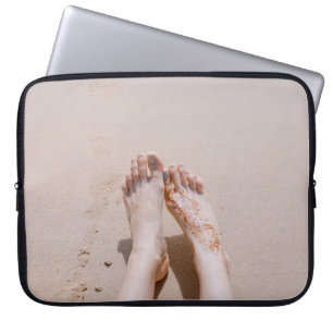 Selective focus photography of feet with tattoo on laptop sleeve