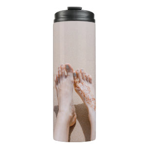 Selective focus photography of feet with tattoo on thermal tumbler