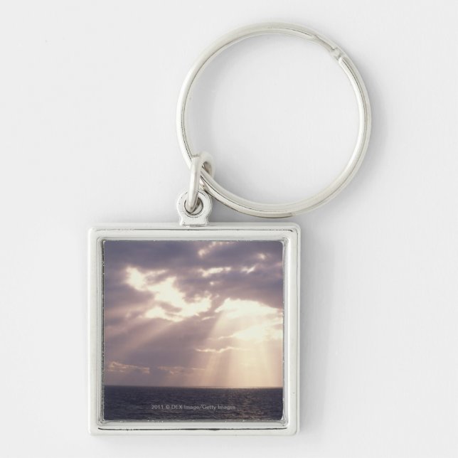 Setting sun shining through clouds over ocean key ring (Front)