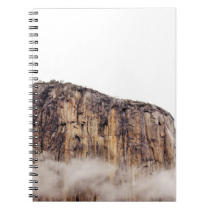 Sheer cliff rising above clouds spiral notebook