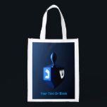 Shiny Blue Dreidel Reusable Grocery Bag<br><div class="desc">A modernistic,  metallic blue dreidel against a dark,  night-like background.  Two of the Hebrew letters found on a dreidel,  nun and shin,  glow brightly.  Add your own text.</div>