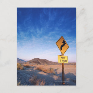 Sign on the death valley road in sunset postcard