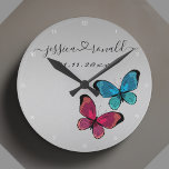 Silvery Grey Names Date Wedding Gift Personalised Round Clock<br><div class="desc">Beautiful connected by love silvery grey wall clock celebrating a couple and their love. Personalised with the couple's names written in cursive script and connected with a swirly heart. It's additionally personalised with a custom date. Decorated with a cute illustration of two butterflies, one purple one blue. Trendy, modern, and...</div>
