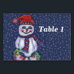 Smiling Snowman Holding String of Christmas Lights Table Number<br><div class="desc">This table number card for your parties or events has a smiling snowman with a carrot nose wearing a winter blue and red hat and scarf holding a lit string of colourful Christmas lights on a dark blue background with falling snow.  Customise your table number with the template.</div>