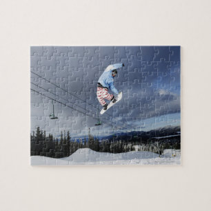 Snowboarder jumping in mid-air doing a backside jigsaw puzzle