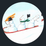 Snowmen on a Sled Classic Round Sticker<br><div class="desc">These three snowmen on a sled have been hand painted by Michelle Meyer and are racing down the snowy,  white hill. Two of them are having a great time while the third has already lost his hat and carrot nose,  and is trying desperately to hang on to his head!</div>