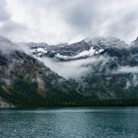Snowy mountains in the fog at Plansee lake  