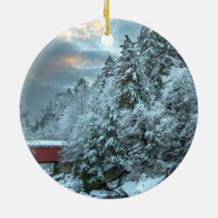 Snowy pines above a covered bridge round ornament