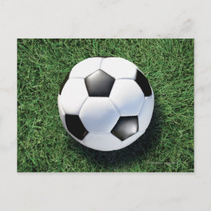 Soccer ball on green grass, close-up postcard