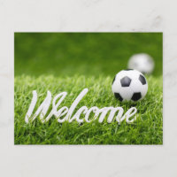 Soccer ball on green grass with welcome sign