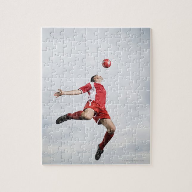 Soccer player and soccer ball in mid-air jigsaw puzzle (Vertical)