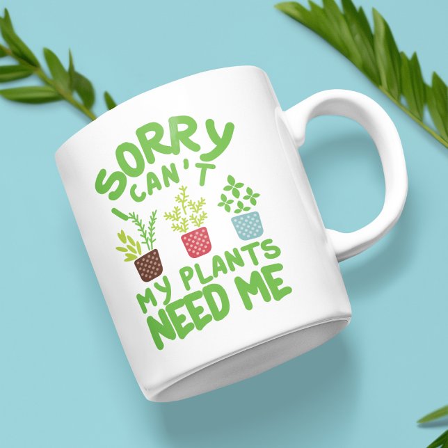 SORRY I CAN'T MY PLANTS NEEDS ME COFFEE MUG (White mug with the text "Sorry, I can't, my plants need me" and colorful plant illustrations.)