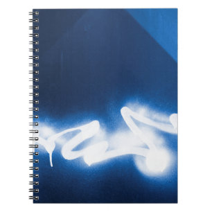 Sprayed graffiti on blue metal spiral notebook