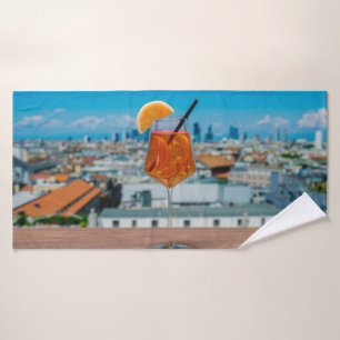 Spritz cocktail on a table with view of Milan Bath Towel