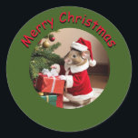 Sticker - Mouse Santa<br><div class="desc">Mouse dressed in Santa Suit is delivering packages under a tree. Text "merry Christmas" in red with a black drop-shadow on a medium green background. #generativecontent</div>