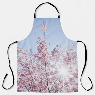 sun rays pass through pink flowers of a wow tree apron