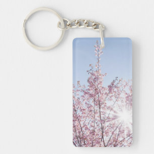 sun rays pass through pink flowers of a wow tree key ring