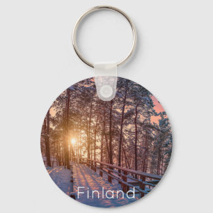 Sunset in snowy pine forest with sun ray key ring