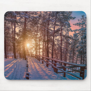 Sunset in snowy pine forest with sun ray mouse pad