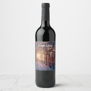 Sunset in snowy pine forest with sun ray wine label