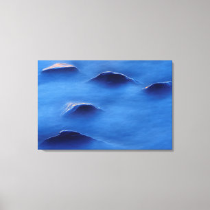 Sunset on rocks protruding through foamy water canvas print