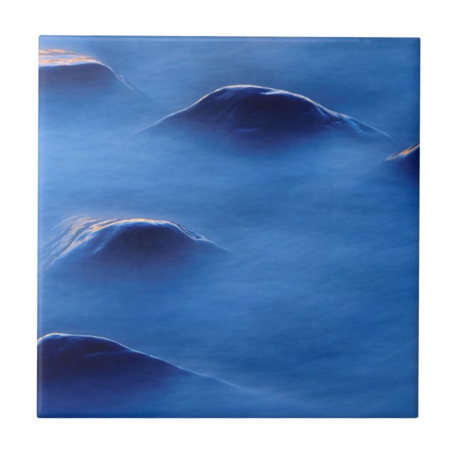 Sunset on rocks protruding through foamy water tile (Front)