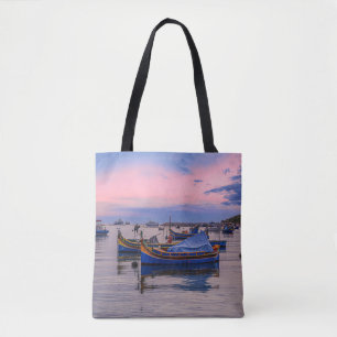 Sunset over harbor with fishing boats tote bag