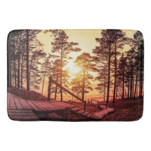 Sunset over wooden path in pine forest bath mat
