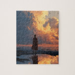 Sunset Solitude: Woman in Red Dress Jigsaw Puzzle<br><div class="desc">A dramatic and contemplative scene captured on a rocky shoreline at sunset. A solitary woman, viewed from behind and wearing a flowing red dress, stands and gazes up at a colossal, sun-drenched cumulonimbus cloud formation. The powerful, warm orange and gold hues of the setting sun dominate the massive clouds, creating...</div>