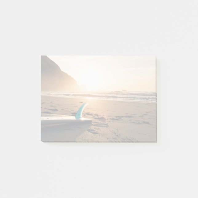 Surfboard lays on the beach as sun appears post-it notes (Front)