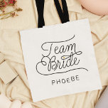 Team Bride Modern Script Gold Wedding Name<br><div class="desc">This modern tote bag with a minimalist casual chic script calligraphy design reading TEAM BRIDE as well as the custom name of your maid of honour or bridesmaid features clean lines to create a sleek and sophisticated appearance. The understated style with the little printed gold heart detail adds a touch...</div>