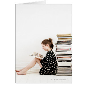 Teenage girl reading comic strip by pile of