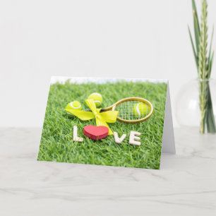 Tennis ball and racket on green grass with love holiday card