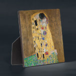 The Kiss by Gustav Klimt Plaque<br><div class="desc">The Kiss by Gustav Klimt The Kiss is an oil-on-canvas painting with added gold leaf, silver and platinum. by the Austrian Symbolist painter Gustav Klimt. It was painted at some point in 1907 and 1908, during the height of what scholars call his "Golden Period". Featuring shimmering gold tones, stylized forms,...</div>