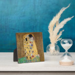 The Kiss by Gustav Klimt Plaque<br><div class="desc">The Kiss by Gustav Klimt The Kiss is an oil-on-canvas painting with added gold leaf, silver and platinum. by the Austrian Symbolist painter Gustav Klimt. It was painted at some point in 1907 and 1908, during the height of what scholars call his "Golden Period". Featuring shimmering gold tones, stylised forms,...</div>