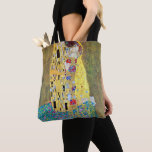 The Kiss by Gustav Klimt, Vintage Art Nouveau Tote Bag<br><div class="desc">Beautiful all-over-print tote bags! Available in two styles and two sizes! The Kiss (Der Kuss) (1907/08) by Gustav Klimt is probably his most famous work. Klimt began work on it in 1907 and it is the highpoint of his so-called 'Golden Period'. The Kiss is a vintage Victorian Era Symbolism fine...</div>