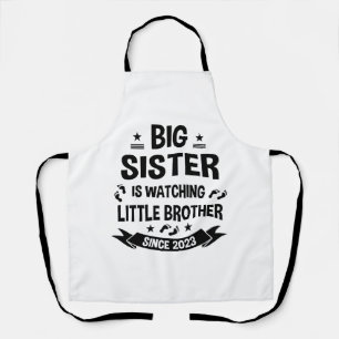 The little sister takes care of the big brother in apron