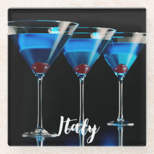Three blue cocktails with cherry on black glass coaster