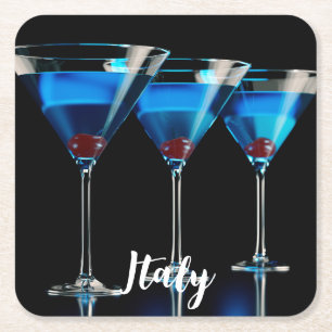 Three blue cocktails with cherry on black square paper coaster