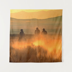 Three cowboy galloping on a background of mountain tapestry