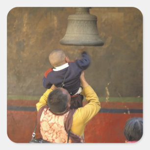 Tibetan Buddhist monk lifting a boy to ring a Square Sticker