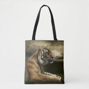 Tiger looking and sitting under dramatic sky tote bag