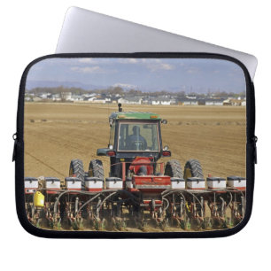 Tractor pulling a seed corn planter. laptop sleeve