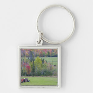 Tractor with hay bale in green field with key ring